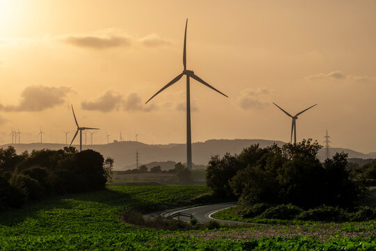 Road in agricultural fields with wind turbines generating clean electricity in Catalonia Spain