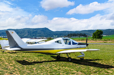 Single engine ultralight airplane waiting to take off at the airfield with blue sky and field background