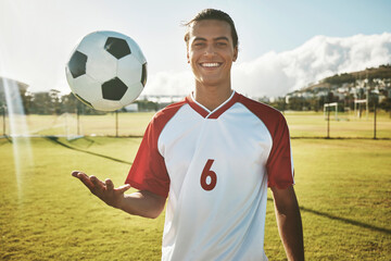 Soccer, portrait and man on a field for training, sports or game in summer. Happy, excited and young athlete catching a football during exercise, fitness and cardio on a sport ground in a park