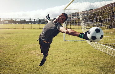 Soccer, sports and goalkeeper training on a field for a professional competition. Young and strong athlete with energy and motivation catching a football during a game or exercise on a sport ground - Powered by Adobe