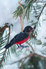 Hanging retro style bird Christmas toy on spruce and over blurred background