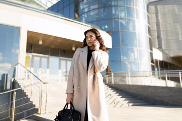 portrait of a successful business woman manager 35 years old talking on a mobile phone against the...