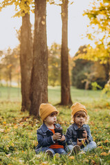 Two little brothers sitting on grass and drinking tea