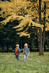 Fototapeta premium Two boys brothers running in an autumn park