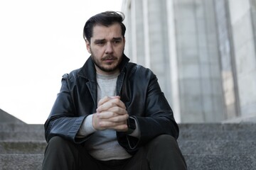 portrait of a man sitting on the steps in emotional distress with guilt on his face