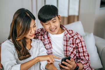 Happy Young Asian couple use smartphone enjoy to play game
