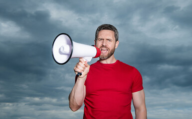 man in red shirt proclaim in loudspeaker on sky background
