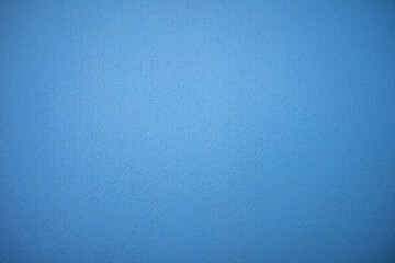 Photo of the texture of a blue background made of felt fabric. Clear blue background for text. Woven material for furniture cladding and manufacturing.