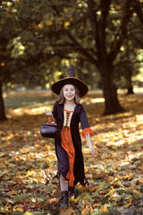 Vertical image of girl in witch outfit and walking in the woods