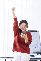 Excited happy Asian woman looking at the phone screen celebrating an online win business 2023, overjoyed young asian female screaming with joy, isolated over a white blur background.
