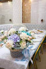 a bouquet of beige and blue flowers in a basket on the background of the festive table