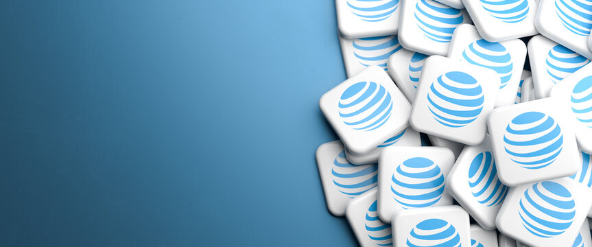 Logos of the telecommunications company AT&T on a heap on a table. Copy Space, web banner format