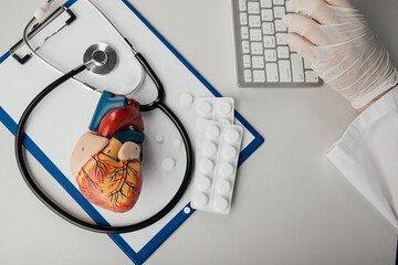 Stethoscope, clipboard, pills and heart model on a cardiologist's table