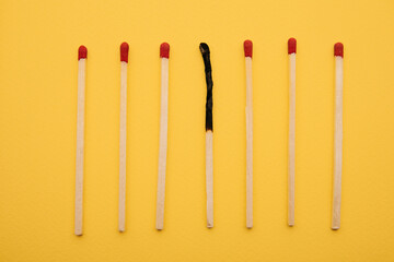 Matchsticks with one burned out on a yellow background