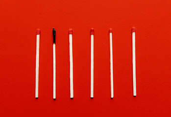 Matchsticks with one burned out on a red background
