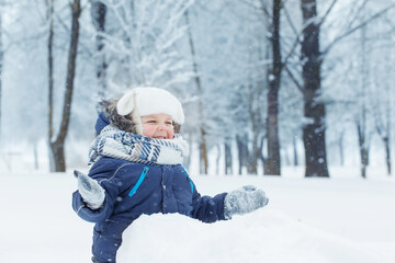 Fototapeta na wymiar little happy boy in snowy winter park