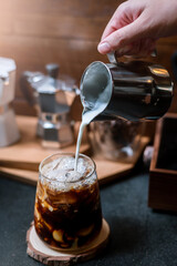 Barista pouring milk in glass