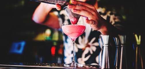 man hand bartender making pink cocktail in glass on the bar counter