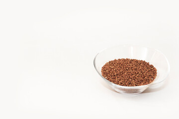 small grains of natural brown buckwheat in a transparent glass plate