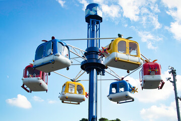 青空を背景に、楽しい遊園地のカラフルな空飛ぶ乗り物