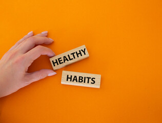 Healthy habits symbol. Concept word Healthy habits on wooden blocks. Beautiful orange background. Businessman hand. Business and Healthy habits concept. Copy space