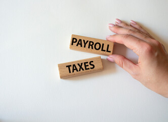Payroll taxes symbol. Concept word Payroll taxes on wooden blocks. Beautiful white background. Businessman hand. Business and Payroll taxes concept. Copy space