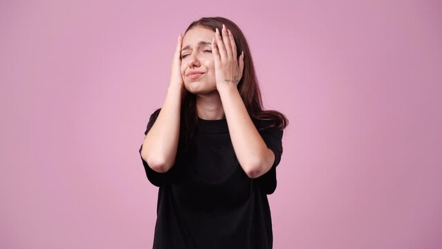 4k video of young woman thinking and looking to the side over pink background..