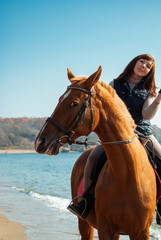 Fototapeta premium Selective focus. Girl and horse. Horse riding by the sea.