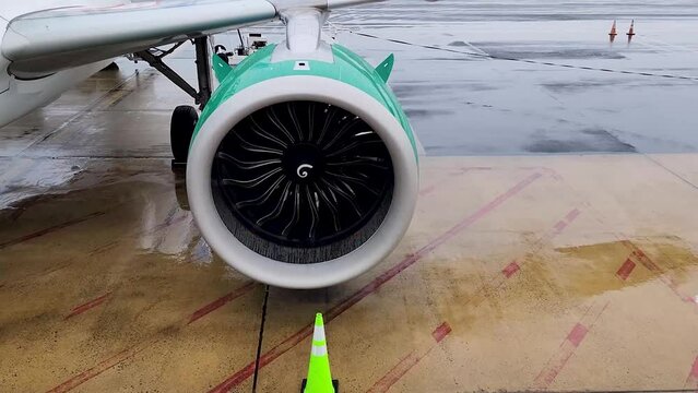 Airbus A320NEO engine blades slowly rotate on a wet day viewed from slightly above.