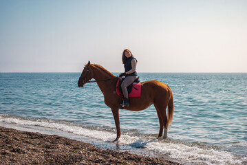 Selective focus. Girl and horse. Horse riding by the sea.