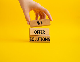 We offer solutions symbol. Concept words We offer solutions on wooden blocks. Beautiful yellow background. Businessman hand. Business and We offer solutions concept. Copy space.