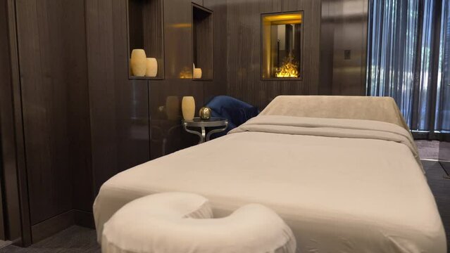 Empty Spa Room With Massage Table And Artificial Fireplace Decoration. wide