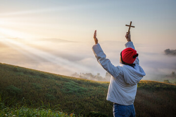 Child holding christian cross Prayer to God beautiful sunrise or sunset background.christian...