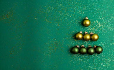 Alternative green and yellow christmas balls make tree on jade green background with gold colored...