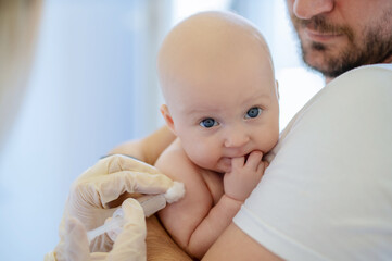 Pediatric doctor vaccinating the neonate in father arms