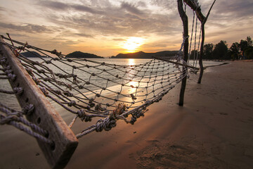 Sunset sea beach travel island with rope hammock and wood swing landmark and twilight cloud sky background landscape in Koh Mak Thailand