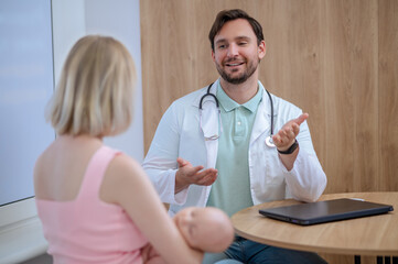 Friendly young pediatrician receiving patients in his office