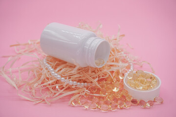 White plastic bottle isolated on pink background. Yellow capsules scattered on a pink background. 