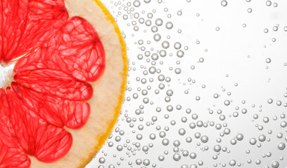 grapefruit slice in clear water with bubbles on a white background