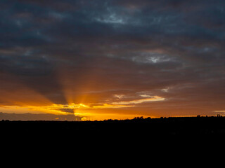 Dramatic sunset nature scene. Warm orange color sky with sun rays and flare. Stunning nature scene at dusk.