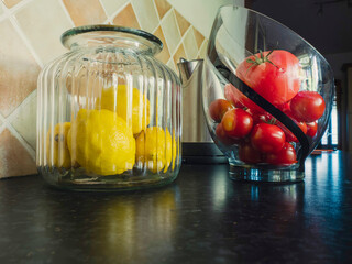 Yellow fresh lemons in a glass jar and red tomato in a glass jar, secondary use as a element of...