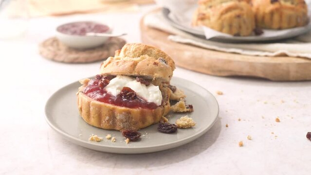 Scones with Strawberry Jam and Clotted Cream with milk served on glass bottle on white kitchen countertop.