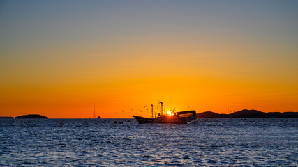 Fototapeta premium Sunset scenery with fishing boats and seagulls. Beautiful sea sunset and fish boat in Korea. Scenery of fishing boats at Changhu-ri dock in Ganghwa-do, Incheon. Korean sea landscape. Korea's West Sea.