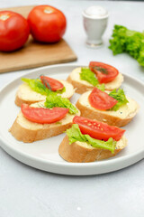 Bruschetta sandwich bread toast with soft white cheese ricotta,fresh tomatoes,basil greenery on a wooden cutting board.Tasty healthy vegetarian food,Italian cuisine appetizer. top view flat lay