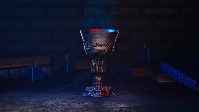 Medieval chalice or goblet with a blue smoke in a dark basement. Magic.