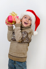 Cute boy in Santa's hat holding gift in two hands and happy smiling