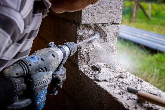 Ouvrier utilisant un perforateur pour percer un mur d'agglos