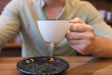 man's hands hold a cup of coffee on the table.