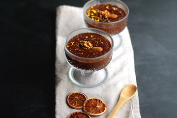 Bowl of homemade chocolate chia pudding, made with dark chocolate, chia seeds, orange juice and plant based milk. Selective focus.