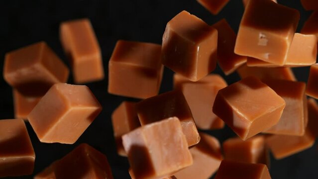 Super Slow Motion Shot of Caramel Pieces Exploded Towards Camera Isolated on Black at 1000fps.